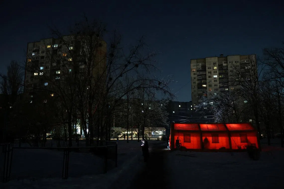 A resident stands near tents of a government-run humanitarian aid points, where residents can warm up, charge their devices, get hot drinks and psychological support, installed next to apartment buildings, during a power blackout after critical civil infrastructure was hit by overnight Russian missile and drone strikes, amid Russia's attack on Ukraine, in Kyiv, Ukraine, January 20, 2026. REUTERS/Anatolii Stepanov