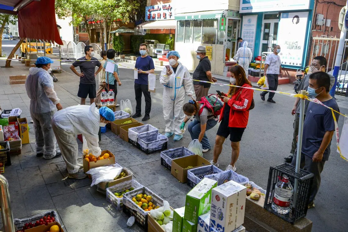Residents standing behind a cordon line shop at a fruit stall amid the coronavirus disease (Covid-19) outbreak, in Tianshan district of Urumqi, Xinjiang Uyghur Autonomous Region, China September 5, 2022. 