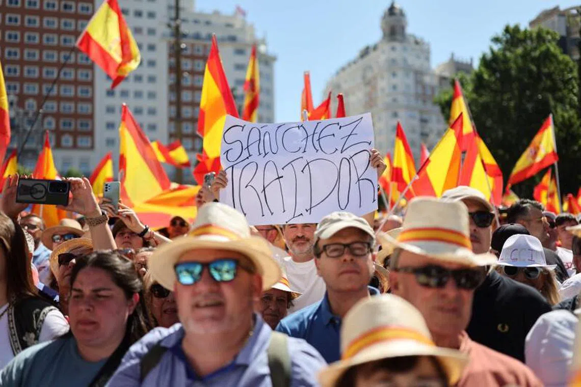 A demonstrator holds a sign reading '(Spain's Prime Minister) Sanchez traitor' during a demonstration called by Spain's right-wing opposition party Partido Popular (PP) to protest against the ruling government in Plaza de Espana square in Madrid on June 8, 2025. (Photo by Thomas COEX / AFP)