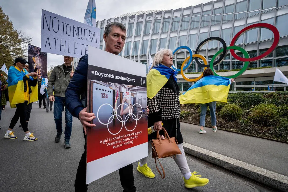Ukrainians walk past the IOC's headquarters in Switzerland to protest against the return to competition of Russian athletes under a neutral flag.