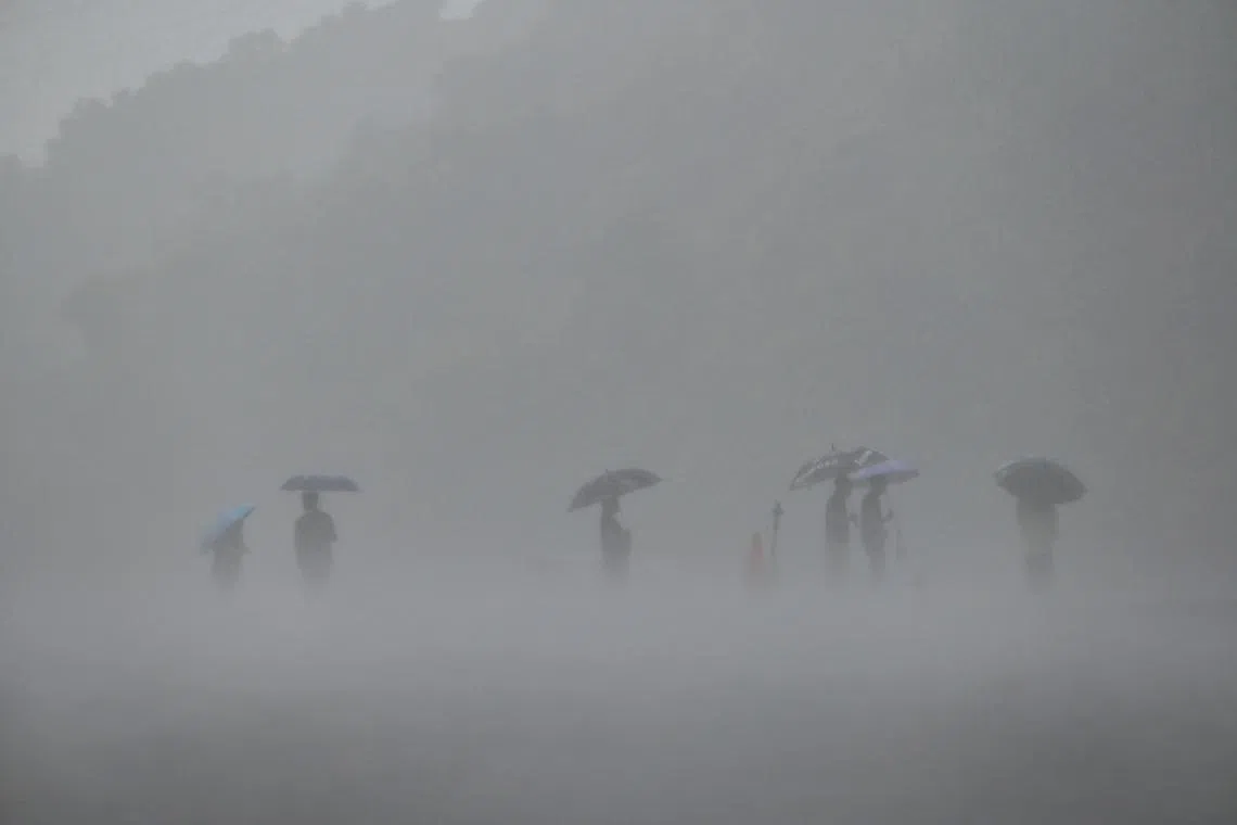 People using umbrellas to shield themselves from the rain in New Taipei City as typhoon Mawar approaches on the east coast of Taiwan on May 31, 2023. 