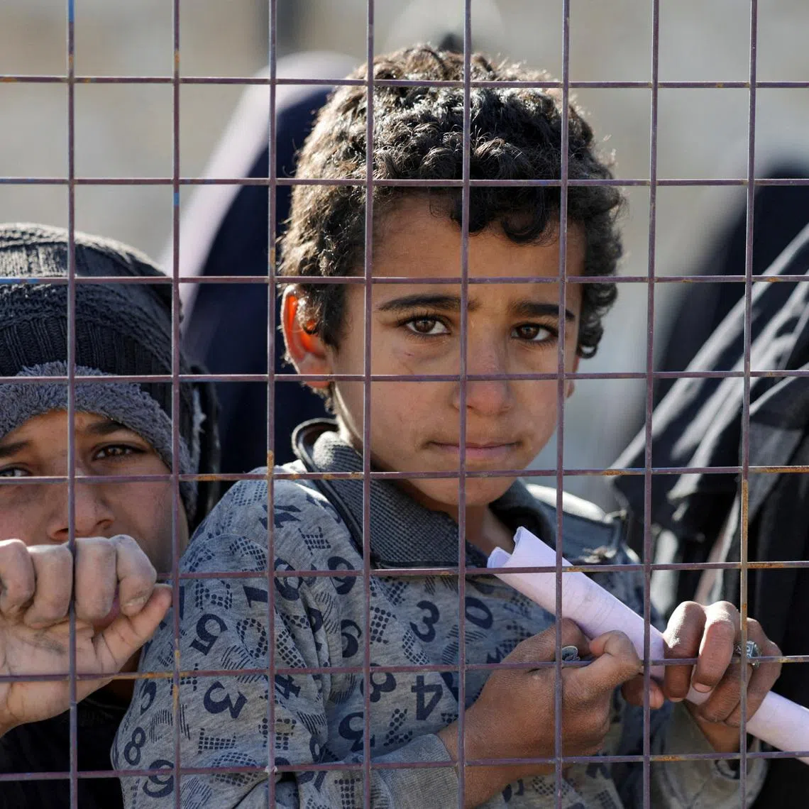 Children, part of a group of detainees, look through a fence at al-Hol camp after the Syrian government took control of it following the withdrawal of Syrian Democratic Forces (SDF), in Hasaka, Syria, January 21, 2026. REUTERS/Khalil Ashawi