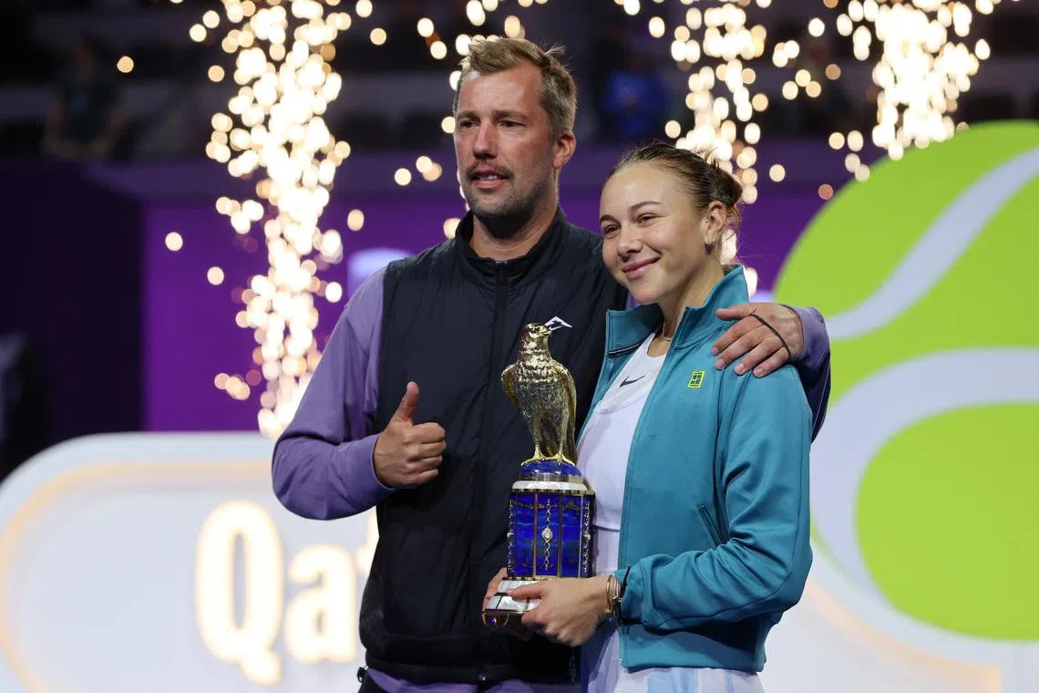 Tennis - Qatar Open - Final - Khalifa International Tennis and Squash Complex, Doha, Qatar - February 15, 2025 Amanda Anisimova of the U.S. celebrates with the trophy and coach Rick Vleeshouwers after winning the final against Latvia's Jelena Ostapenko REUTERS/Ibraheem Al Omari