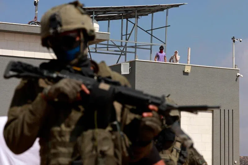 An Israeli soldier standing in front of a Palestinian house in the village of Qusra,  in the occupied West Bank, after rogue settlers blockaded Palestinian homes.