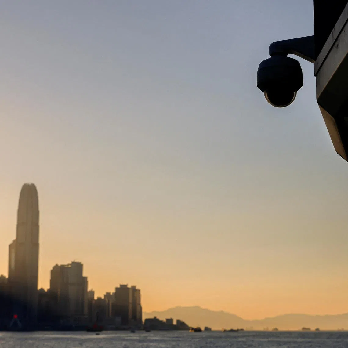 A surveillance camera is seen by the waterfront as skyline buildings stand across Victoria Harbor, in Hong Kong, China October 24, 2023. REUTERS/Tyrone Siu
