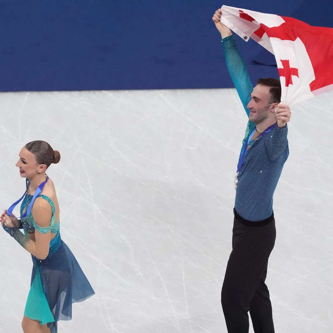 Feb 16, 2026; Milan, Italy;  Anastasiia Metelkina and Luka Berulava of Georgia celebrate with the flag after winning silver n the pairs free skate during the Milano Cortina 2026 Olympic Winter Games at Milano Ice Skating Arena. Mandatory Credit: Amber Searls-Imagn Images