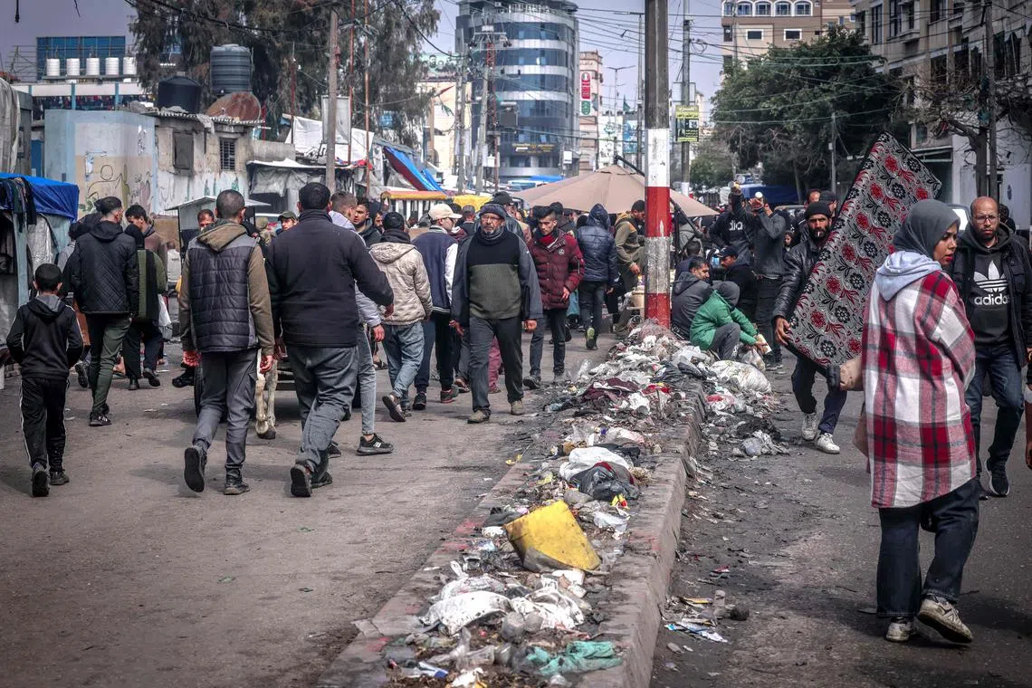 Palestinian walking past piles of garbage in a main street in Rafah, in the southern Gaza Strip, on Feb 19, 2024.