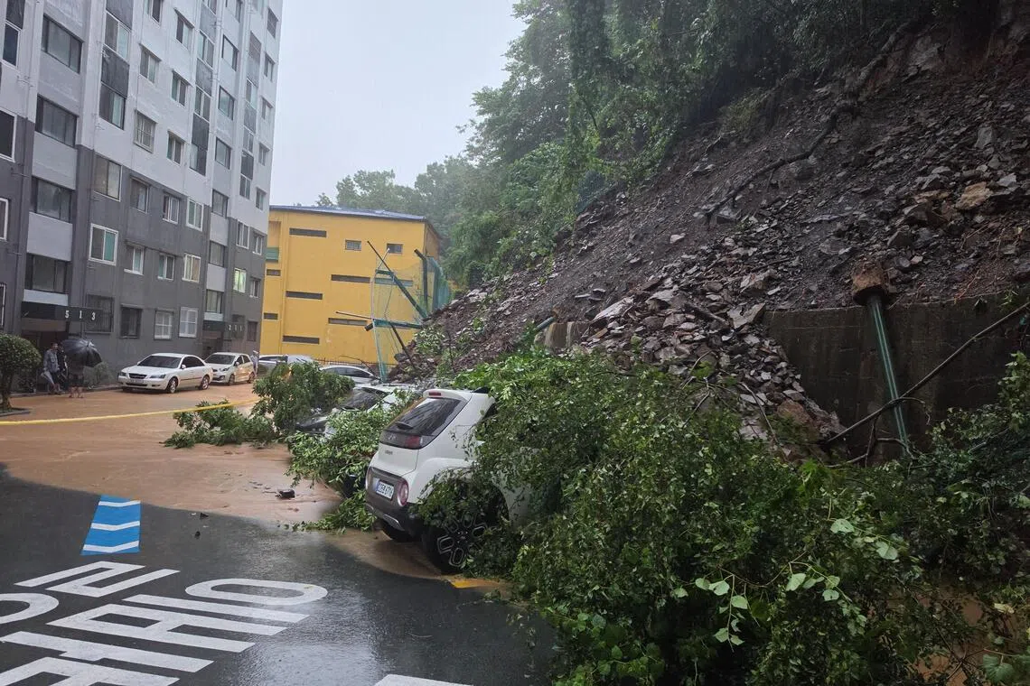 Mud and fallen trees from a landslide cover parked vehicles at an apartment complex in Geoje, South Korea, on Aug 17.