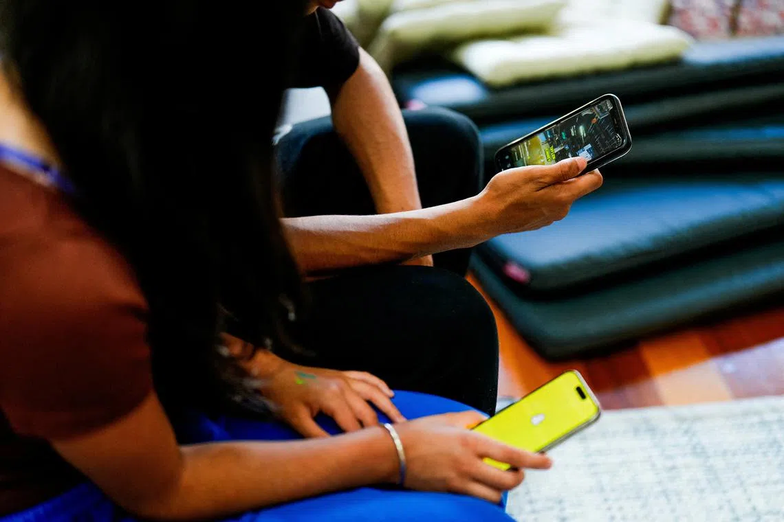 FILE PHOTO: Two school students pose with their mobile showing social media applications in Melbourne, Australia, November 28, 2024. REUTERS/Asanka Brendon Ratnayake/File Photo