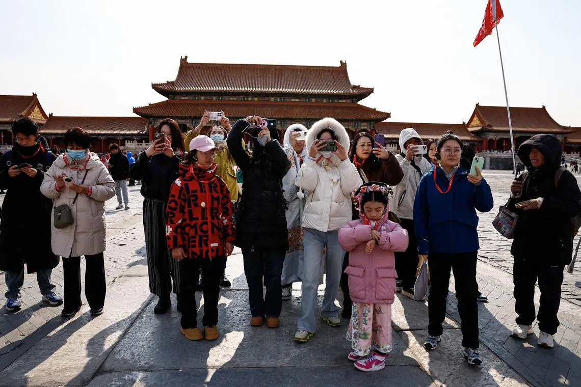 FILE PHOTO: Tourists use their phones as they visit the Forbidden City in Beijing, China February 21, 2025. REUTERS/Tingshu Wang/File Photo