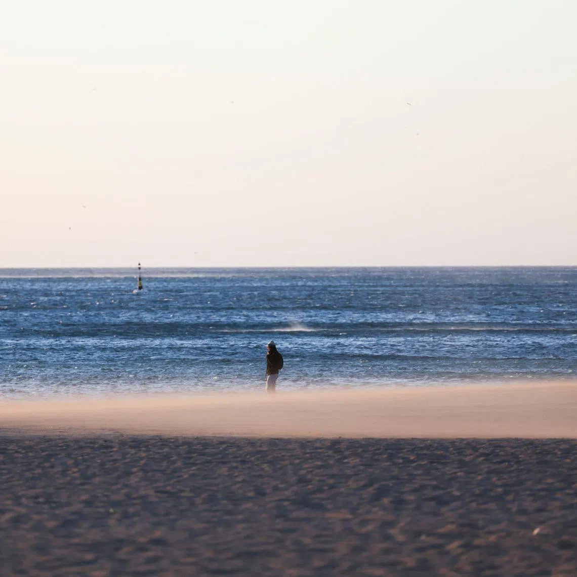 A woman walks on the Barceloneta beach during high winds in Barcelona, Spain, February 12, 2026. REUTERS/Nacho Doce