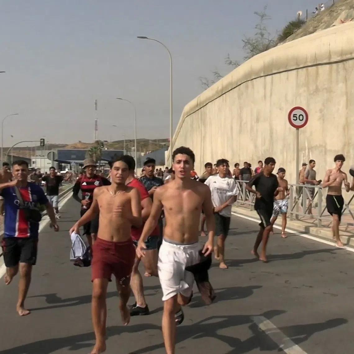 Migrants run and cheer as they cross on foot into the North African enclave of Ceuta from Morocco, on July 310.