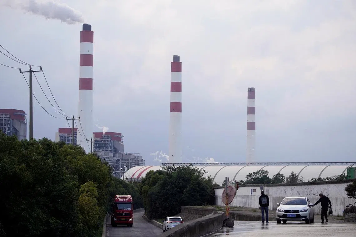 FILE PHOTO: Men stand by a car near a coal-fired power plant in Shanghai, China October 21, 2021. REUTERS/Aly Song/File Photo