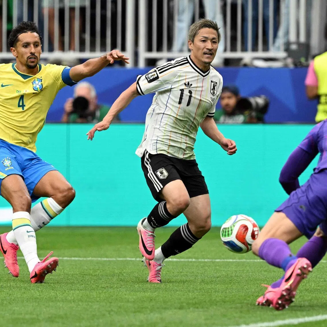 Japan's forward #11 Daizen Maeda (C) runs towards Brazil's goalkeeper #01 Alisson (R) as Brazil's defender #04 Marquinhos (L) looks on during the 2026 World Cup round of 32 football match between Brazil and Japan at the Houston Stadium in Houston on June 29, 2026.  (Photo by RONALDO SCHEMIDT / AFP)