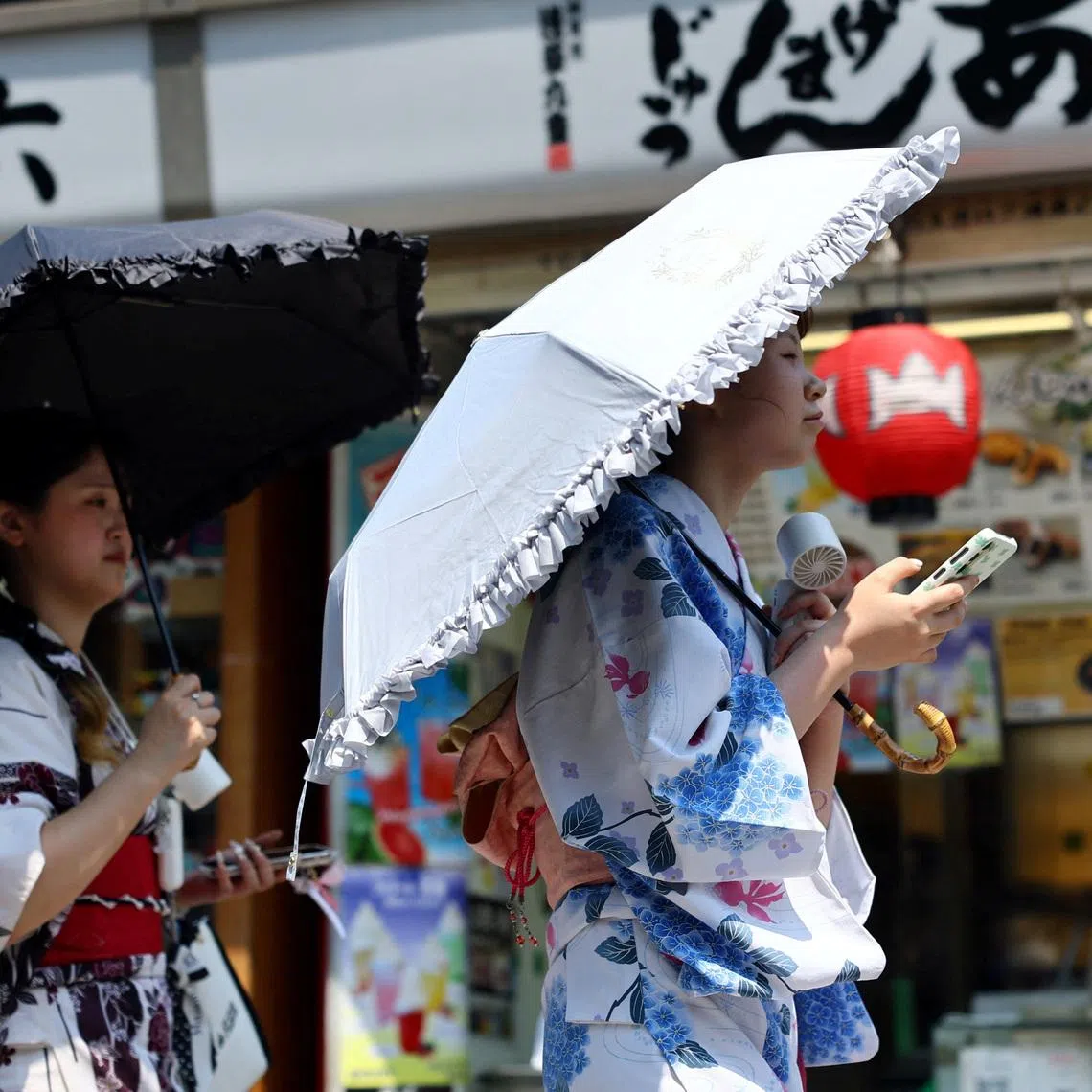 Women wearing yukata, or casual summer kimonos, use portable fans as they walk along Nakamise Street at the Asakusa district, a popular sightseeing spot, as the Japanese government issued a heatstroke alert in Tokyo and other prefectures due to a heatwave, in Tokyo, Japan July 22, 2026.REUTERS/Issei Kato