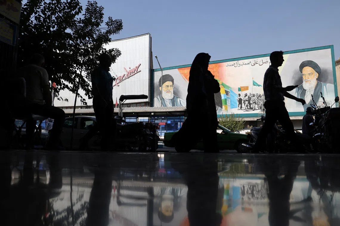 FILE PHOTO: People walk past a mural depicting the late leader of the Islamic Revolution Ayatollah Ruhollah Khomeini and Iran's Supreme Leader Ayatollah Ali Khamenei on a building in a street in Tehran, Iran, October 7, 2024. Majid Asgaripour/WANA (West Asia News Agency) via REUTERS/ File Photo