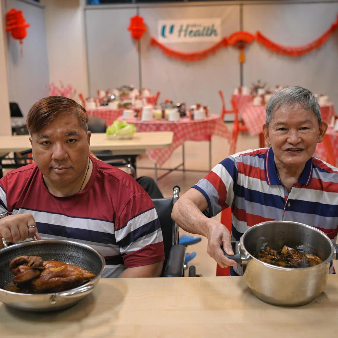 Francis Lim (left), 53, an ex-Hyatt hotel chef and Tan Lam Huat, 74, display their dishes of stewed chicken and pigs trotters, ahead of their reunion dinner with the other residents of the NTUC Health Nursing Home in Jurong West on January 19, 2023.