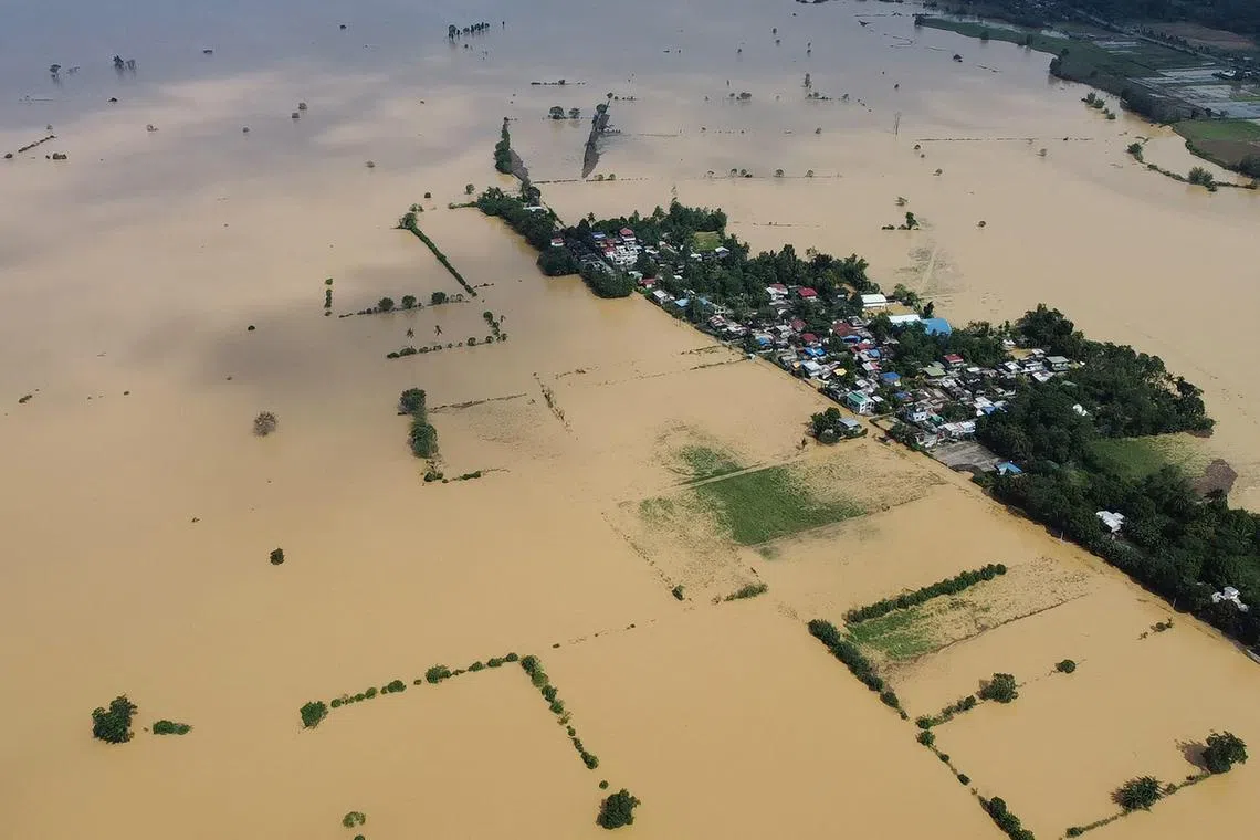 TOPSHOT - An aerial photo shows a swollen river inundating farm fields and houses at a village in Ilagan town, Isabela province on November 12, 2024, a day after Typhoon Toraji hit the province. The Philippines issued fresh weather warnings on November 12 as the fifth major storm in three weeks bore down on the archipelago, days after thousands were evacuated ahead of Typhoon Toraji. (Photo by Villamor VISAYA / AFP)