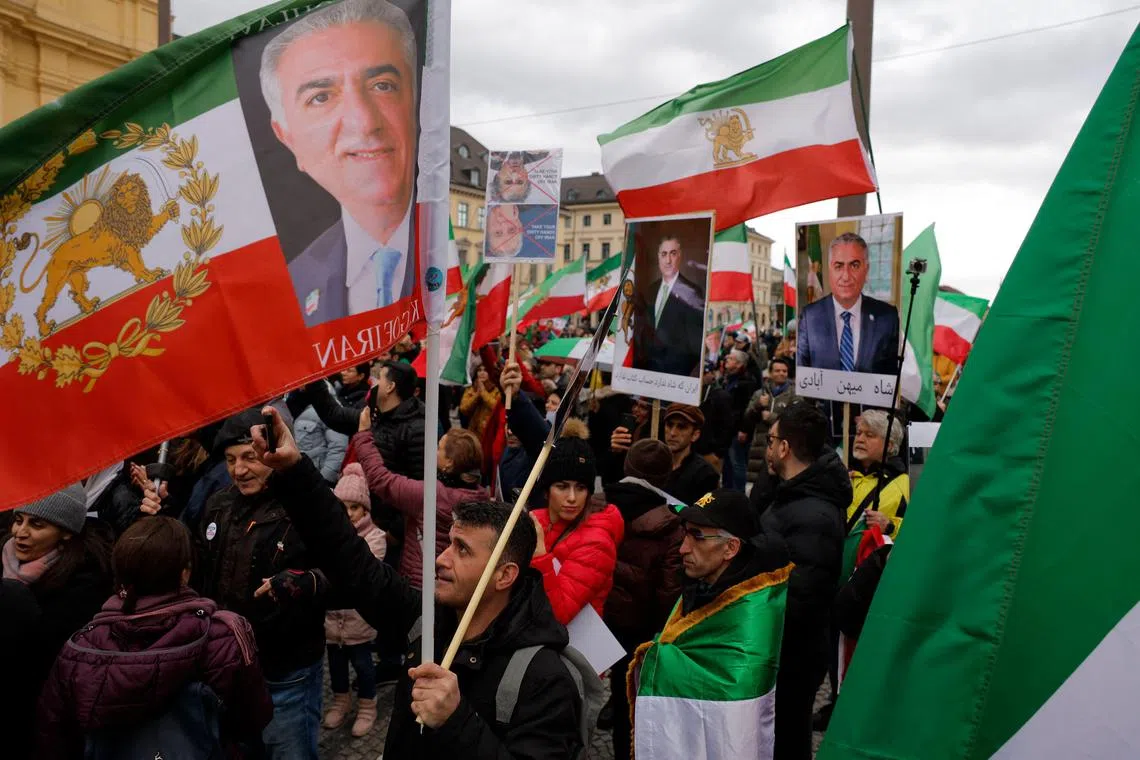 People carry historic flags of Iran and portraits of activist Reza Pahlavi, oldest son of the last Shah of Iran, during a protest on the sidelines of the Munich Security Conference, in February 2023.