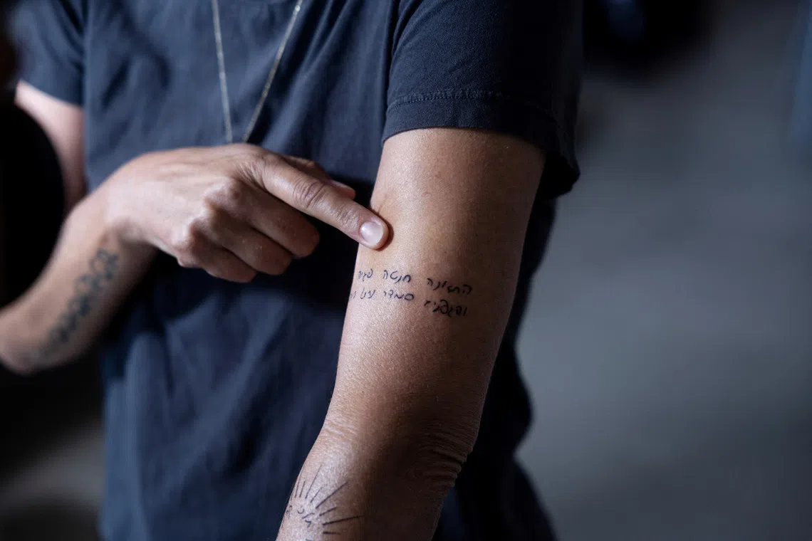 FILE PHOTO: Leron Mor, the aunt and custodian of former hostage Avigail Idan and her siblings Michael and Amalia, who were orphaned when their parents Smadar Idan and Roee Idan were killed during the deadly October 7 attack by Hamas in kibbutz Kfar Aza, points at a tattoo with a quote from the Bible featuring her sister's name, Smadar, in her home in Israel, September 18, 2024. Avigail was three years old when she was taken hostage and later released in a deal, and her siblings survived by hiding in a cabinet while their mother lay dead on the floor beside them. REUTERS/Ronen Zvulun/File Photo