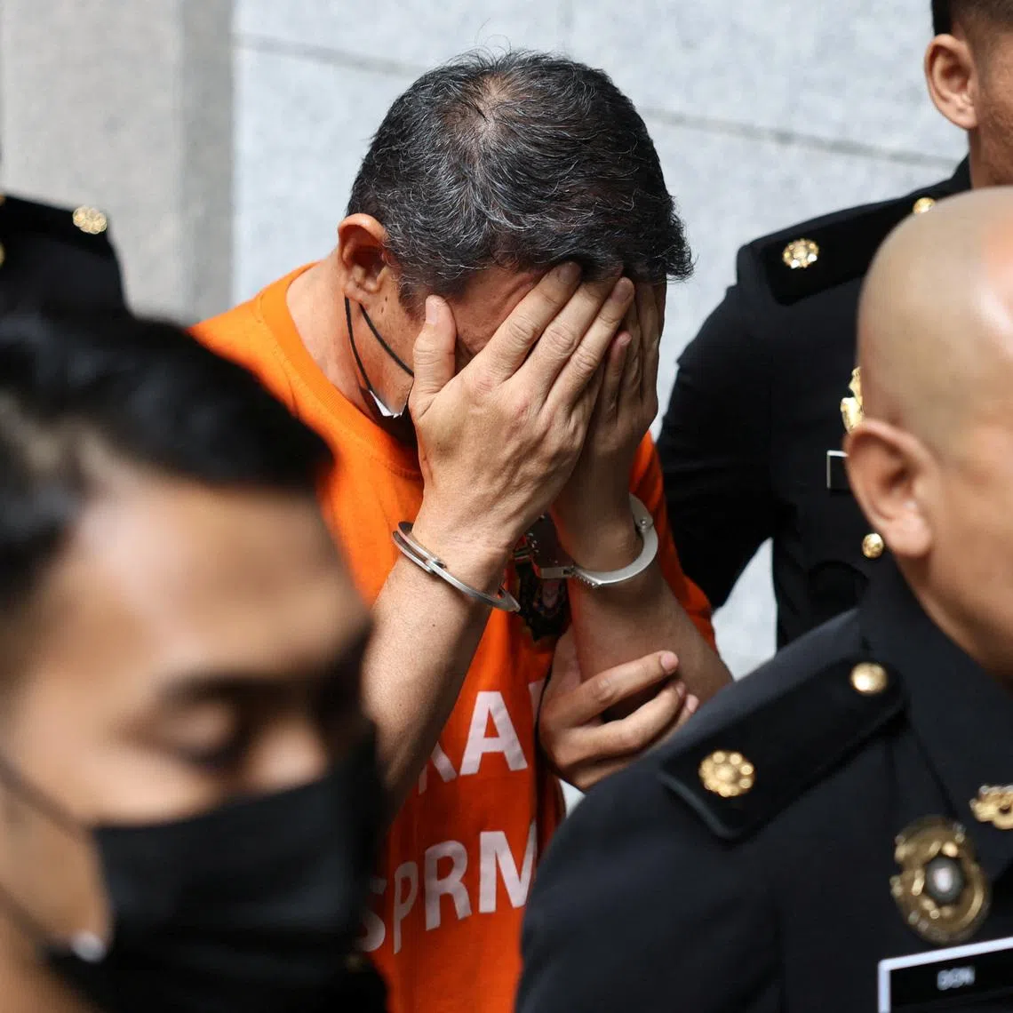 Malaysian anti-graft officers escort a former army chief, while leaving the court complex after the authorities managed to get a court order to hold him in custody to assist in an investigation into alleged bribery involving military procurement contracts, in Putrajaya, Malaysia January 8, 2026. REUTERS/Hasnoor Hussain.