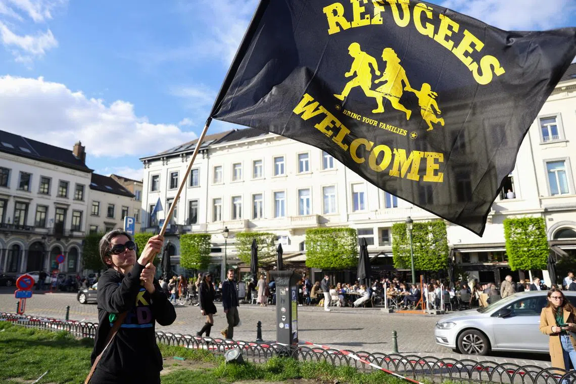 A woman waves a flag as human rights activists protests outside the European Parliament ahead of a vote by lawmakers on the EU's Pact on Asylum and Migration, in Brussels, Belgium April 10, 2024. REUTERS/Johanna Geron
