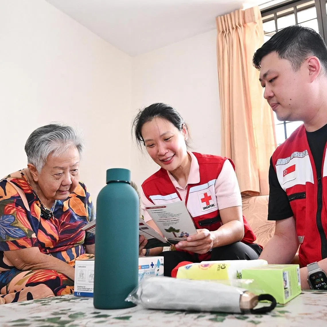 (From left) Madam Magdalene Tan with Singapore Red Cross representatives Charis Chan and Alan Phuang at her flat on April 6.