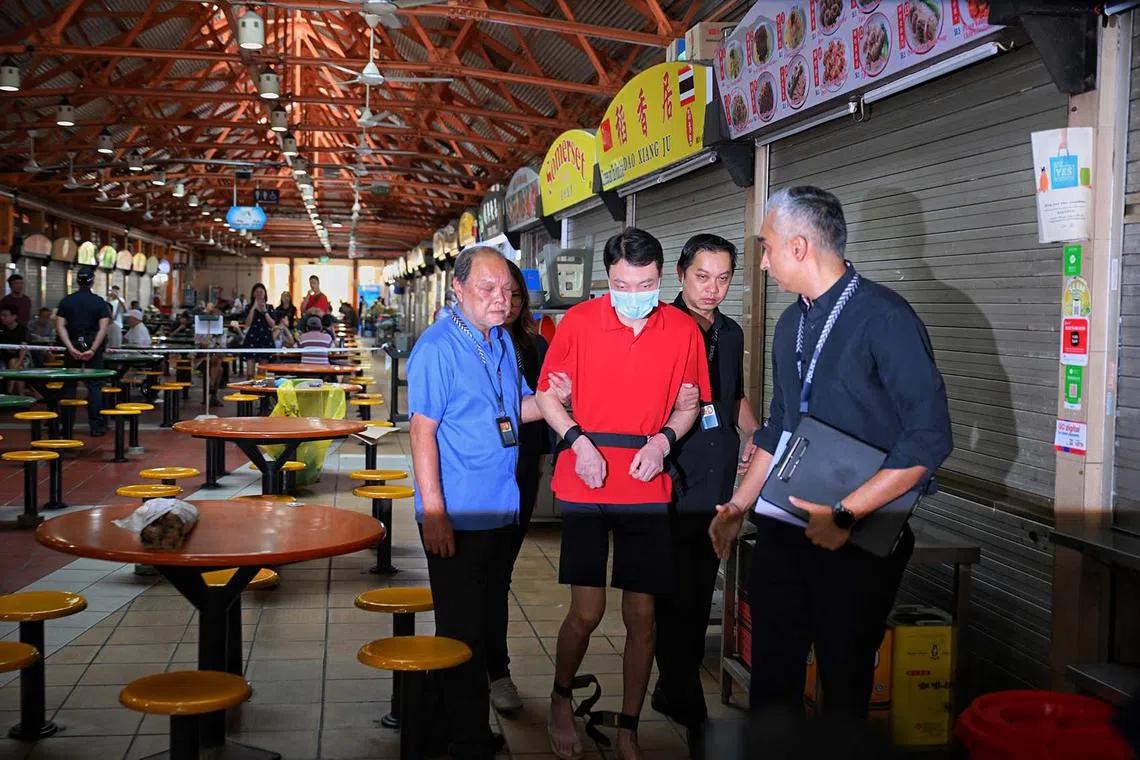 Wu Tao, 41, who is accused of killing Ms Tan Kamonwan, 48, inside a stall at Maxwell Food Centre in Kadayanallur Street, was brought back to the site by the police for a visit on Oct 15, 2024.