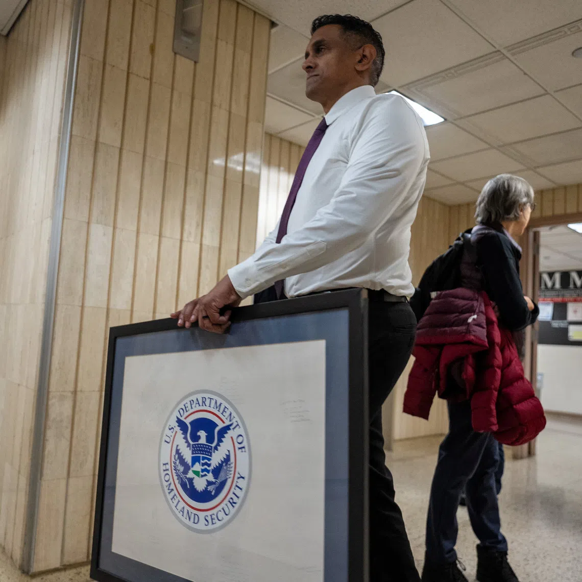 FILE PHOTO: A person carries a framed logo of U.S. Department of Homeland Security in the hallway of U.S. immigration court in Manhattan, in New York City, U.S., January 13, 2026. REUTERS/David 'Dee' Delgado/File photo