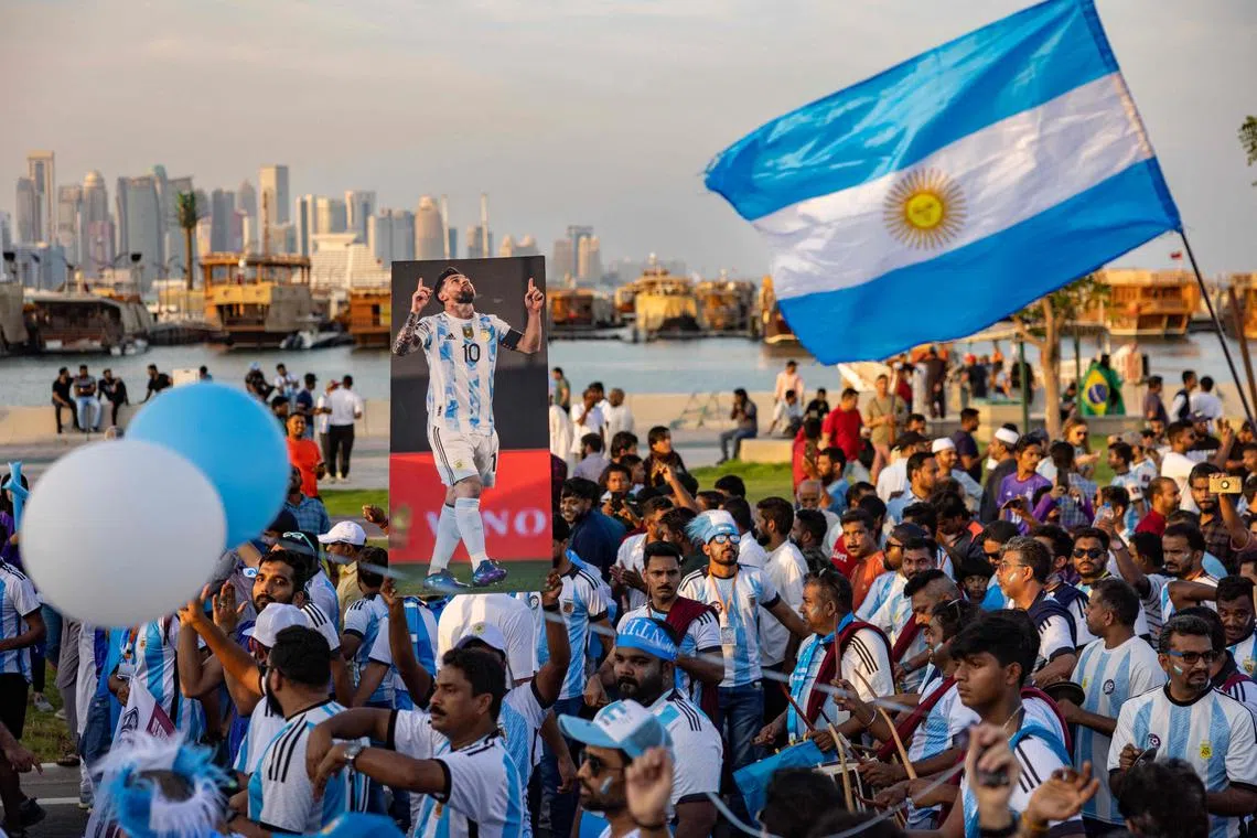 Football fans, many of them migrant workers in Doha, cheer as they demonstrate their support for Argentina at a waterfront in Doha on Friday. 