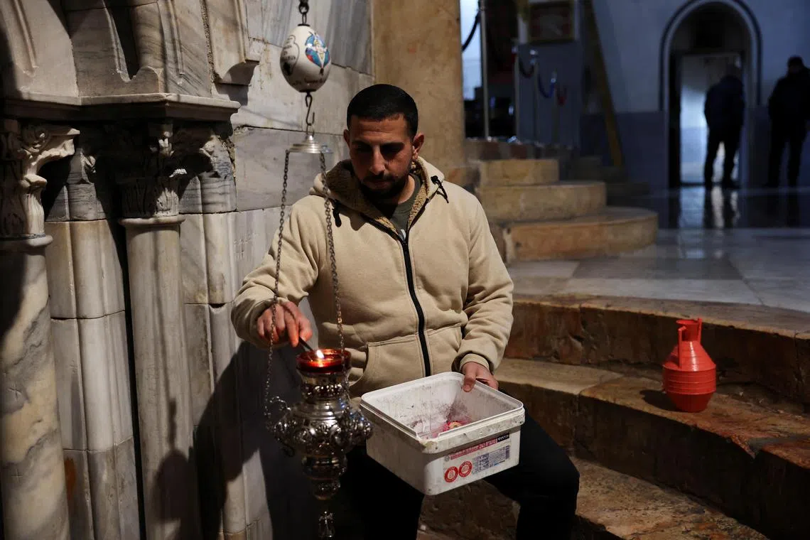 A Palestinian changes candles in the Church of the Nativity, in Bethlehem in the Israeli-occupied West Bank on Dec 23, 2023. 