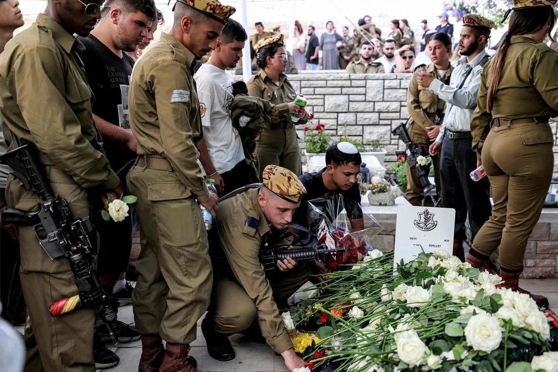 A soldier lays flowers on the coffin during the funeral of Staff Sergeant Ori Izhak Iluz, one of three Israeli soldiers killed in the cross-border incident with Egypt, at a cemetery in the city of Safed in northern Israel on June 4, 2023. Israel said on June 4 that it would investigate the shooting deaths of three soldiers at its border with Egypt, as it prepared to hold funerals for the slain trio. On June 3, three Israeli soldiers were killed by an "Egyptian policeman" who had entered the country and was shot dead in a rare cross-border incident, the army said. (Photo by Jalaa MAREY / AFP)