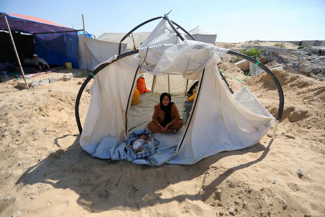 A displaced Palestinian woman and a child shelter in a cemetery, as Gaza health ministry announced that death toll has surpassed 40,000, amid the Israel-Hamas conflict, in Khan Younis, in the southern Gaza Strip, August 15, 2024. REUTERS/Hatem Khaled