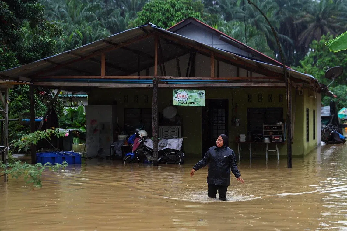 A woman walks through floodwaters in Klang, outside Kuala Lumpur, Malaysia on Nov 24, 2025.  