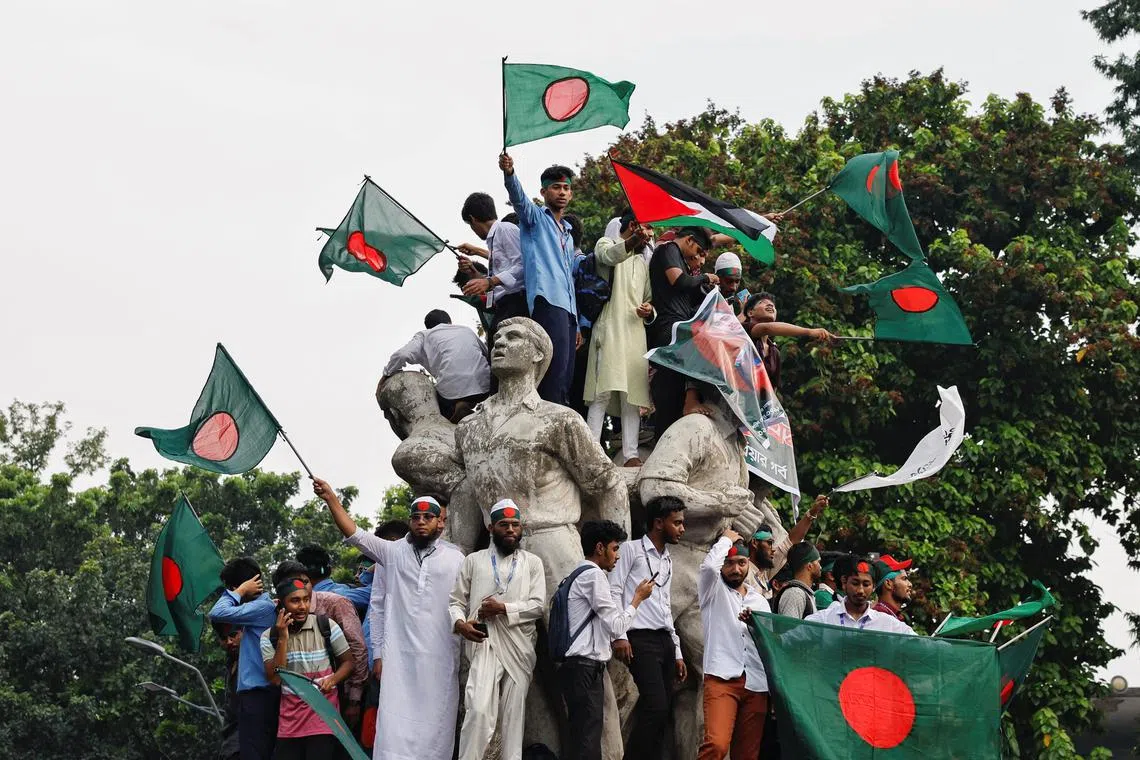 Students against discrimination wave flags by standing on top of Raju Memorial Sculpture as they join in a rally to mark one month of the end of Awami League regime, at the University of Dhaka, in Dhaka, Bangladesh, September 5, 2024. REUTERS/Mohammad Ponir Hossain/File Photo