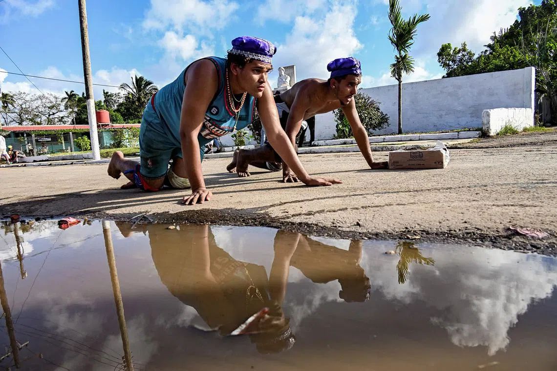TOPSHOT - A couple of Cuban pilgrims participate in the San Lazaro procession at El Rincon church in Havana on December 16, 2024. Thousands of believers gather every year to fulfill their promises to San Lazaro or Babalu Aye. (Photo by YAMIL LAGE / AFP)