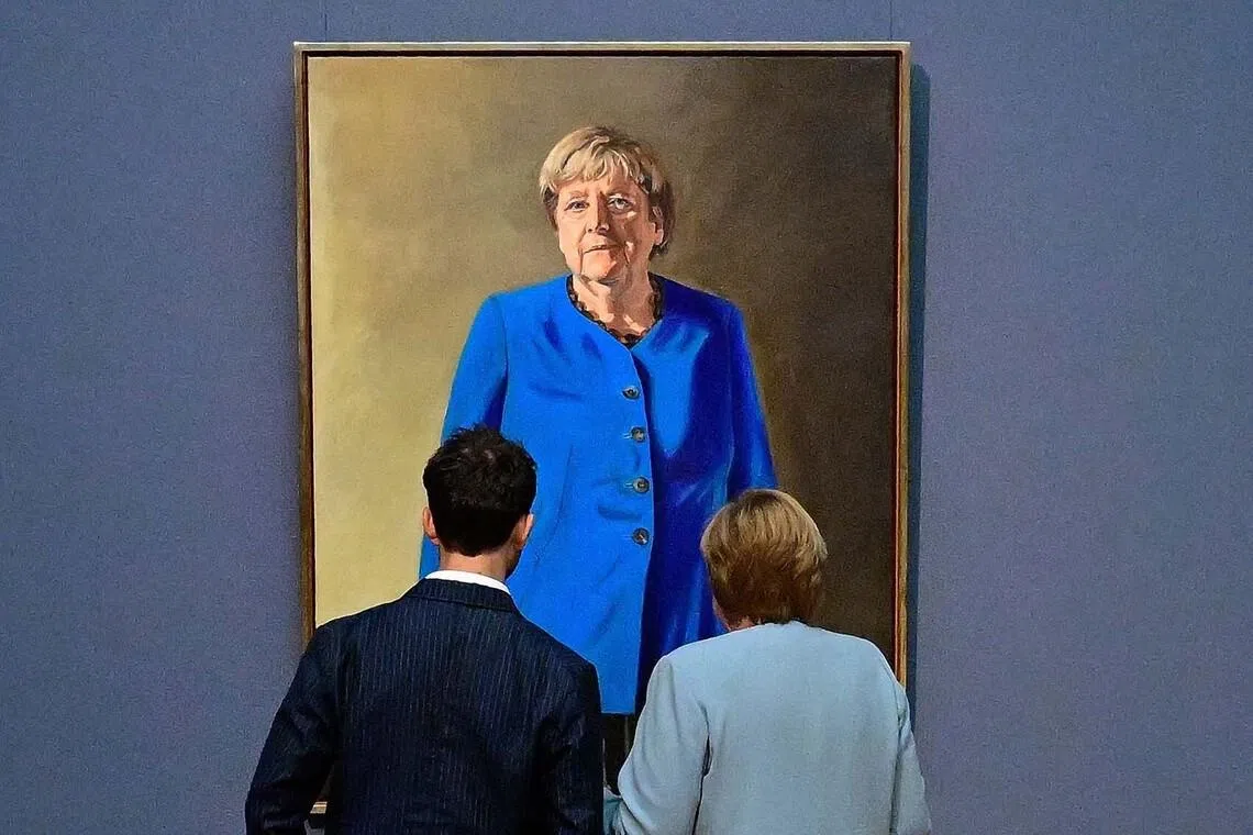 TOPSHOT - Former German chancellor Angela Merkel (R) and French-German artist Jeremie Queyras (L) look at his painting “Portrait of former Federal Chancellor Angela Merkel” after it was unveiled at the Bode Museum in Berlin on June 30, 2026. (Photo by Tobias SCHWARZ / AFP) / RESTRICTED TO EDITORIAL USE - MANDATORY MENTION OF THE ARTIST UPON PUBLICATION - TO ILLUSTRATE THE EVENT AS SPECIFIED IN THE CAPTION