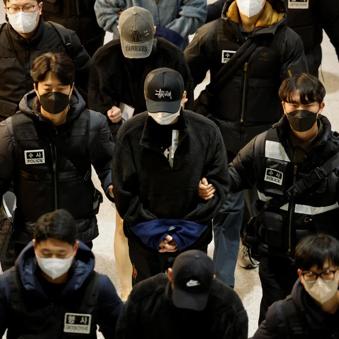 Police officers escort South Koreans allegedly involved in scam operations in Cambodia after being forcibly repatriated from Cambodia, at Incheon International Airport in Incheon, South Korea January 23, 2026. REUTERS/Kim Soo-hyeon