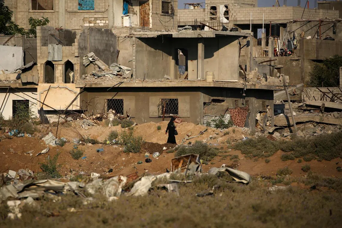 A woman walking past the rubble of buildings destroyed during Israeli bombardment, in the central Gaza Strip, on Aug 2, 2024.