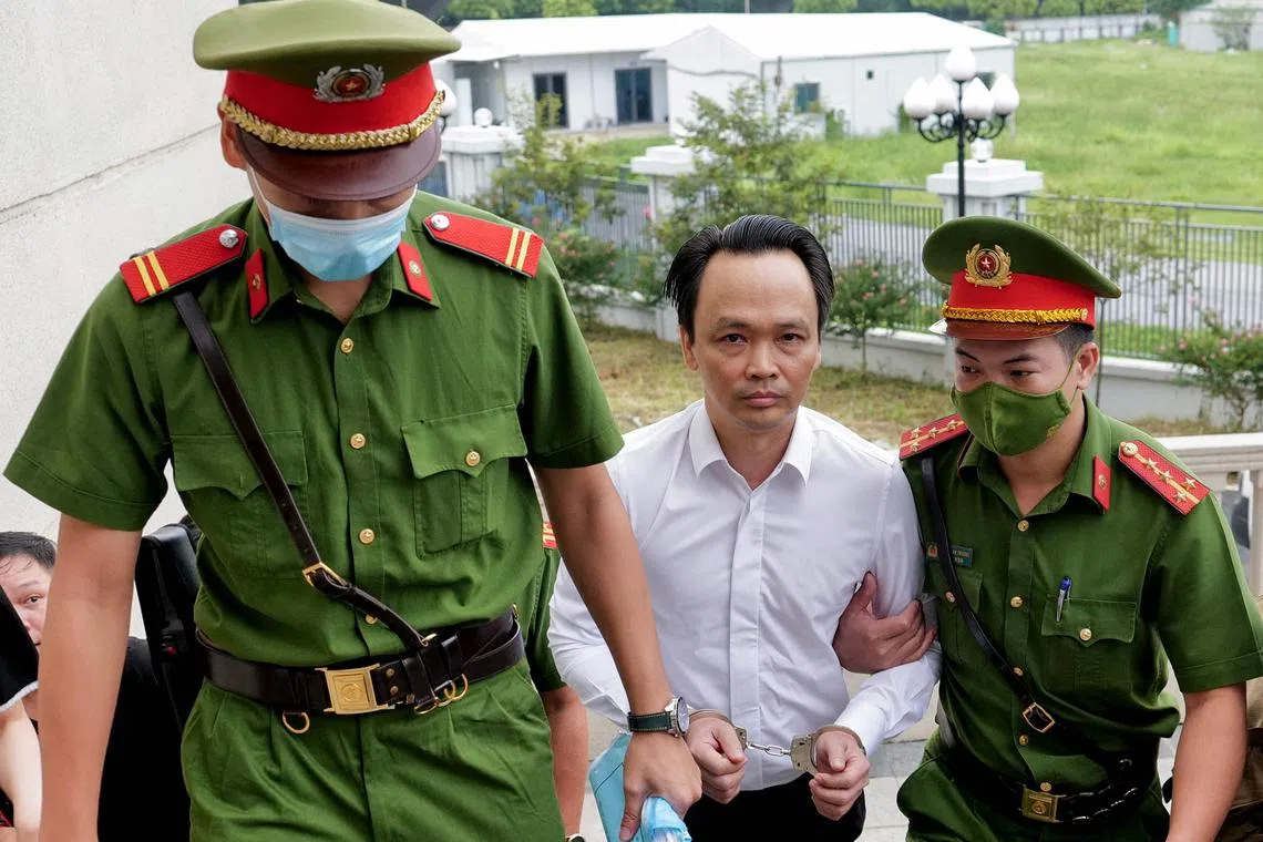 (FILES) Former Vietnamese property and aviation tycoon Trinh Van Quyet (C) is escorted by policemen to court for his trial on fraud charges in Hanoi on July 22, 2024. Trinh Van Quyet, who owned the FLC empire of luxury resorts, golf courses, and budget carrier Bamboo Airways, was jailed for 21 years on August 5 for fraud and stock market manipulation worth $146 million, state media said. (Photo by Anh TUC / AFP)