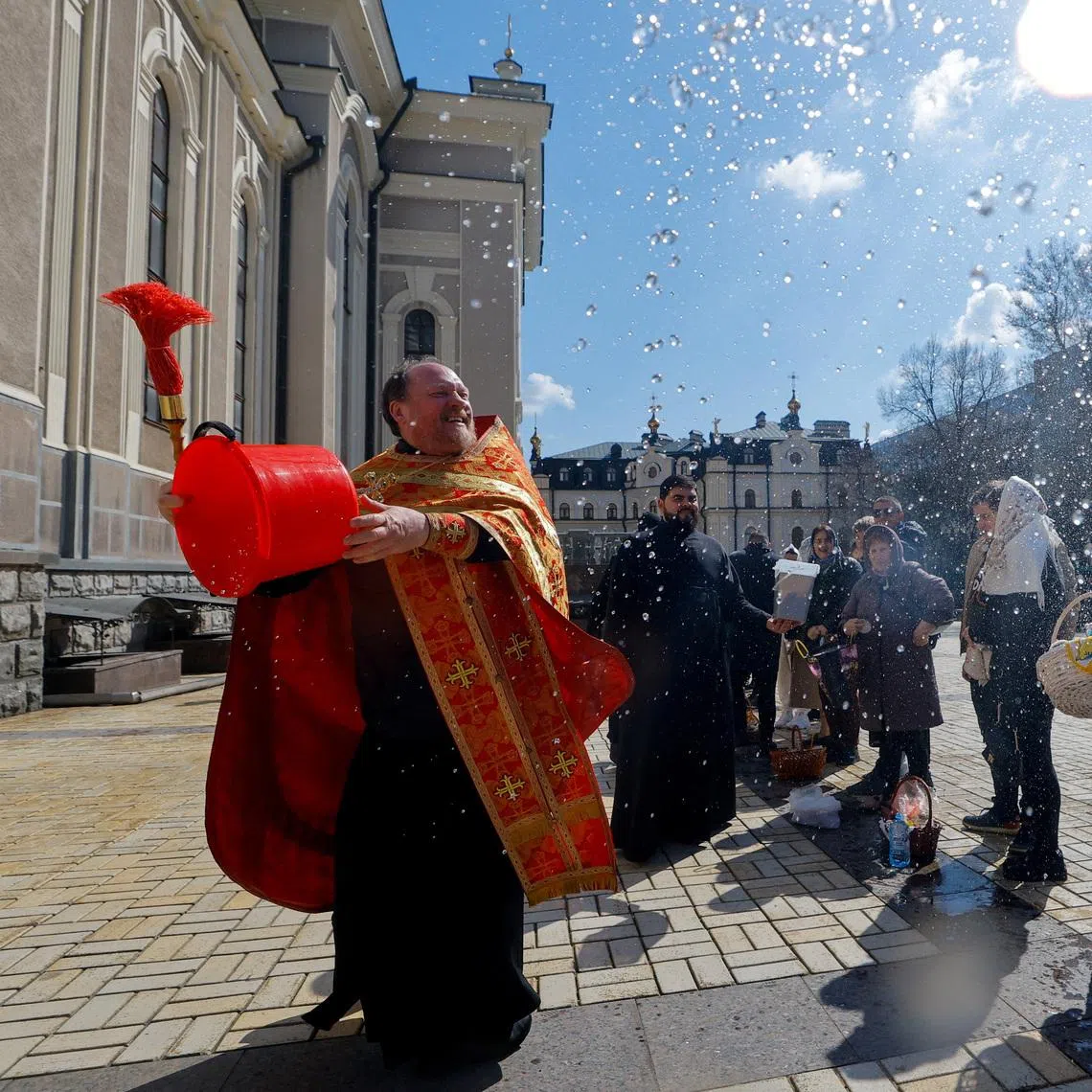 A priest sprays holy water on parishioners outside a cathedral during Orthodox Easter celebrations amid the Russia-Ukraine conflict in Donetsk, a Russian-controlled city of Ukraine, April 12, 2026. REUTERS/Alexander Ermochenko