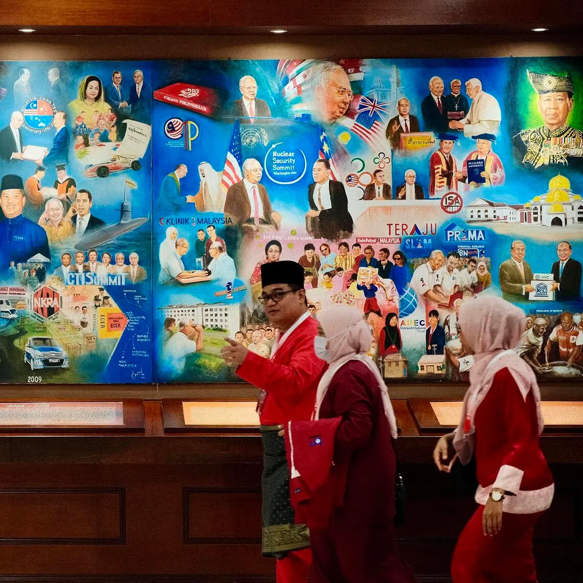 UMNO delegates walk past a mural commemorating former party president and Prime Minister Anwar Ibrahim.