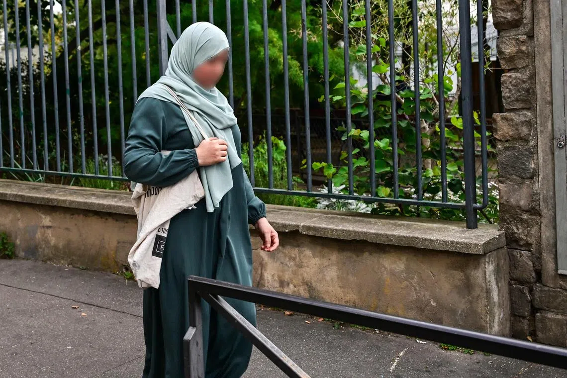 A photograph taken on Aug 28, 2023 shows a Muslim woman wearing an abaya walking in the streets of Paris. France has decided to ban girls from wearing the abaya in schools. 