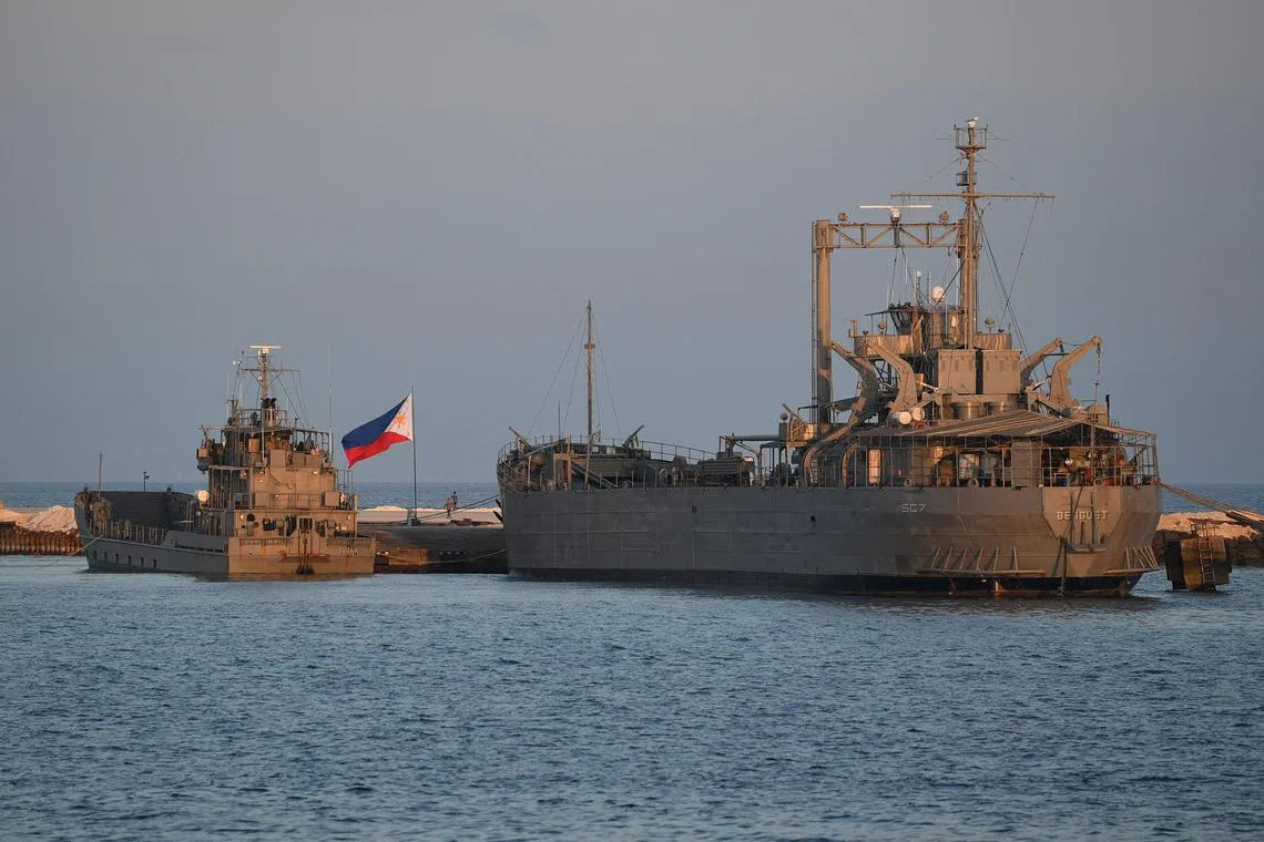 A Philippine flag fluttering next to navy ships anchored at the Philippine-occupied Thitu island in the disputed South China Sea. 