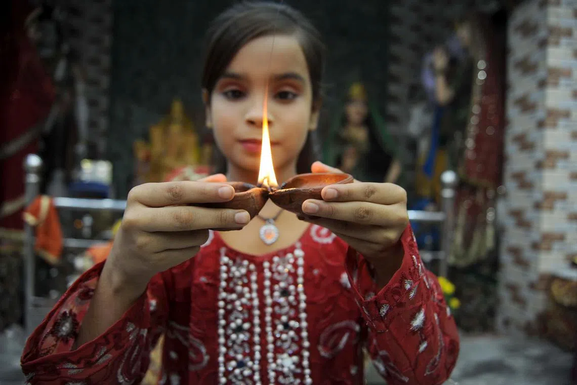 A Pakistani Hindu girl lighting earthen lamps to celebrate the Diwali festival in Hyderabad, Pakistan on Nov 12, 2023. 