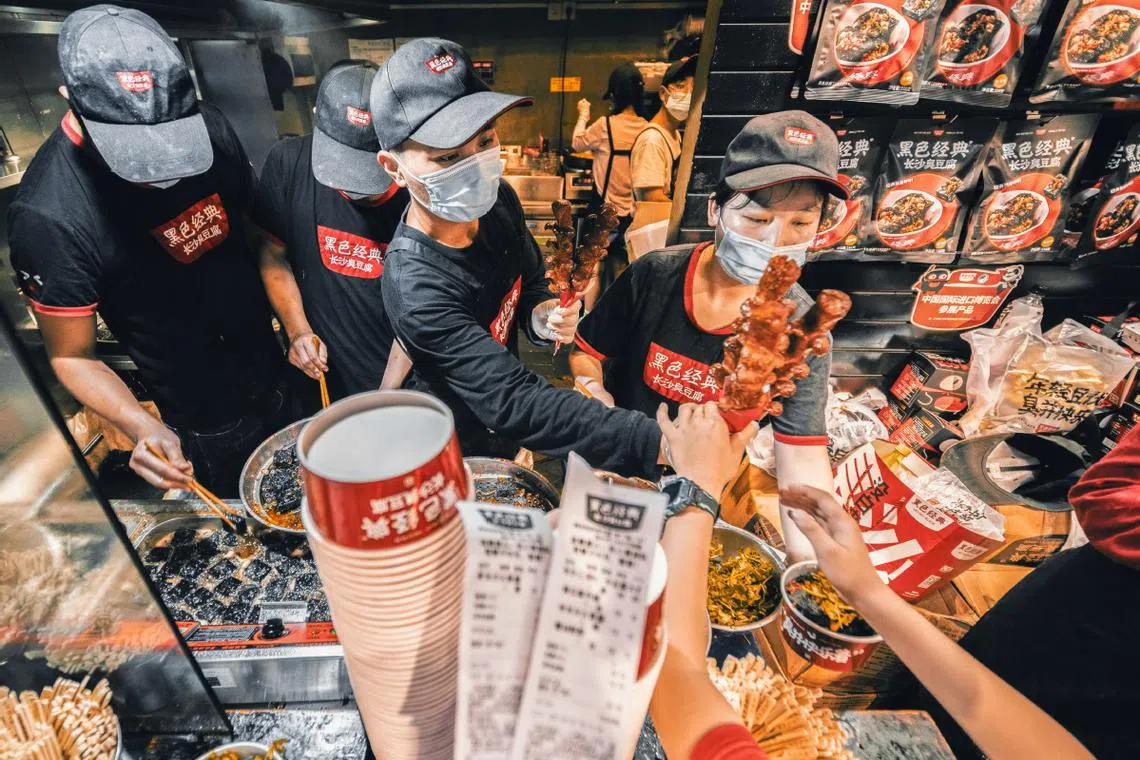Employees prepare stinky tofu snacks at a Hey Hey Black store in Changsha, Hunan province in May 2023.