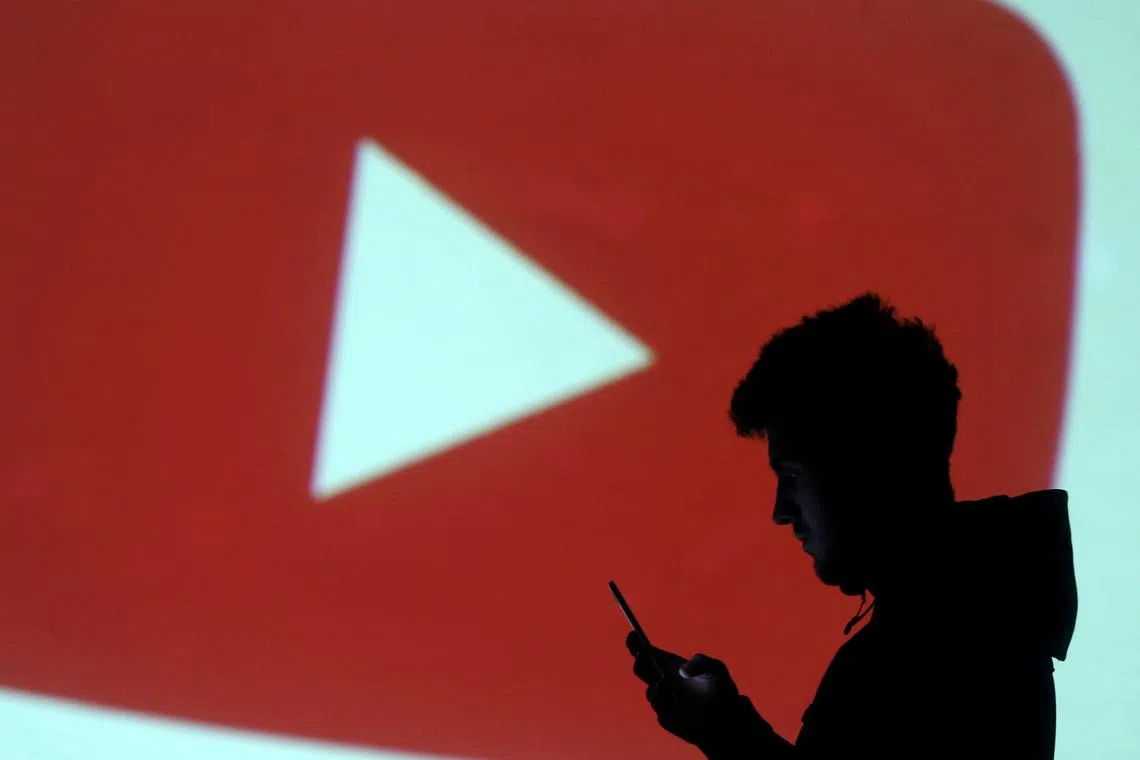 FILE PHOTO: A silhouette of a mobile user is seen next to a screen projection of Youtube logo in this picture illustration taken March 28, 2018.  REUTERS/Dado Ruvic/Illustration/File Photo