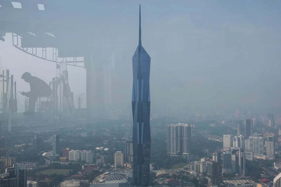 epa13218900 A KL Tower worker waiting for his customer is reflected alongside Merdeka 118, the world's second-tallest building, amid citywide particulate haze in Kuala Lumpur, Malaysia, 07 September 2026. Kuala Lumpur recorded unhealthy air quality, with an air pollutant index (API) reading of 118.  EPA/FAZRY ISMAIL