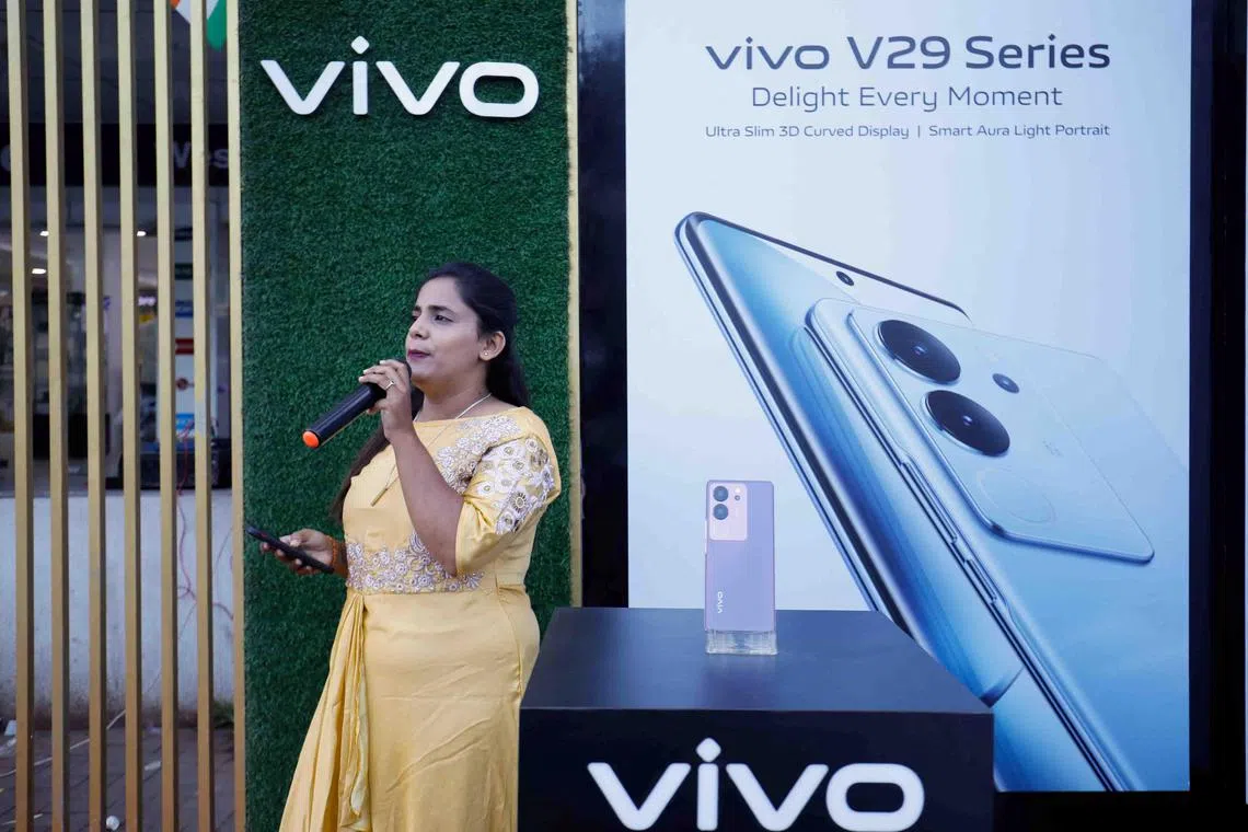 A sales representative promotes a Vivo  smartphone outside a store in Ahmedabad, India.