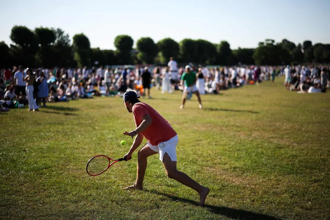Tennis fans play tennis as they queue for tickets on the first day of the 2025 Wimbledon Championships at The All England Lawn Tennis and Croquet Club in Wimbledon, southwest London, on June 30, 2025. 
